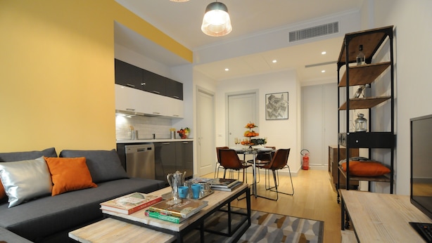 A modern living room with a sofa, coffee table, and a dining area with chairs and a table. - Apartment in Trastevere free wi-fi 1GB/s fiber, AC, equipped kitchen, balcony. (Roma)