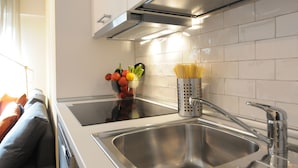 A modern kitchen with a stainless steel sink, a bowl of fresh vegetables, and a container of uncooked pasta. - Apartment in Trastevere free wi-fi 1GB/s fiber, AC, equipped kitchen, balcony. (Roma)