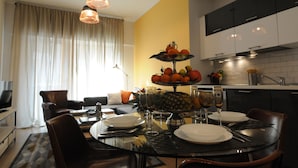 A modern kitchen with black and white cabinets, a dining table set for two with plates, glasses, and cutlery. - Apartment in Trastevere free wi-fi 1GB/s fiber, AC, equipped kitchen, balcony. (Roma)