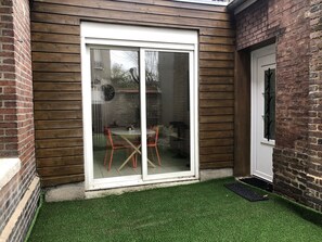 A small patio area with a sliding glass door, a round table, and two chairs.