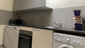 A compact kitchen with a microwave, oven, and washing machine. - Charming apartment, Left bank (Rouen)