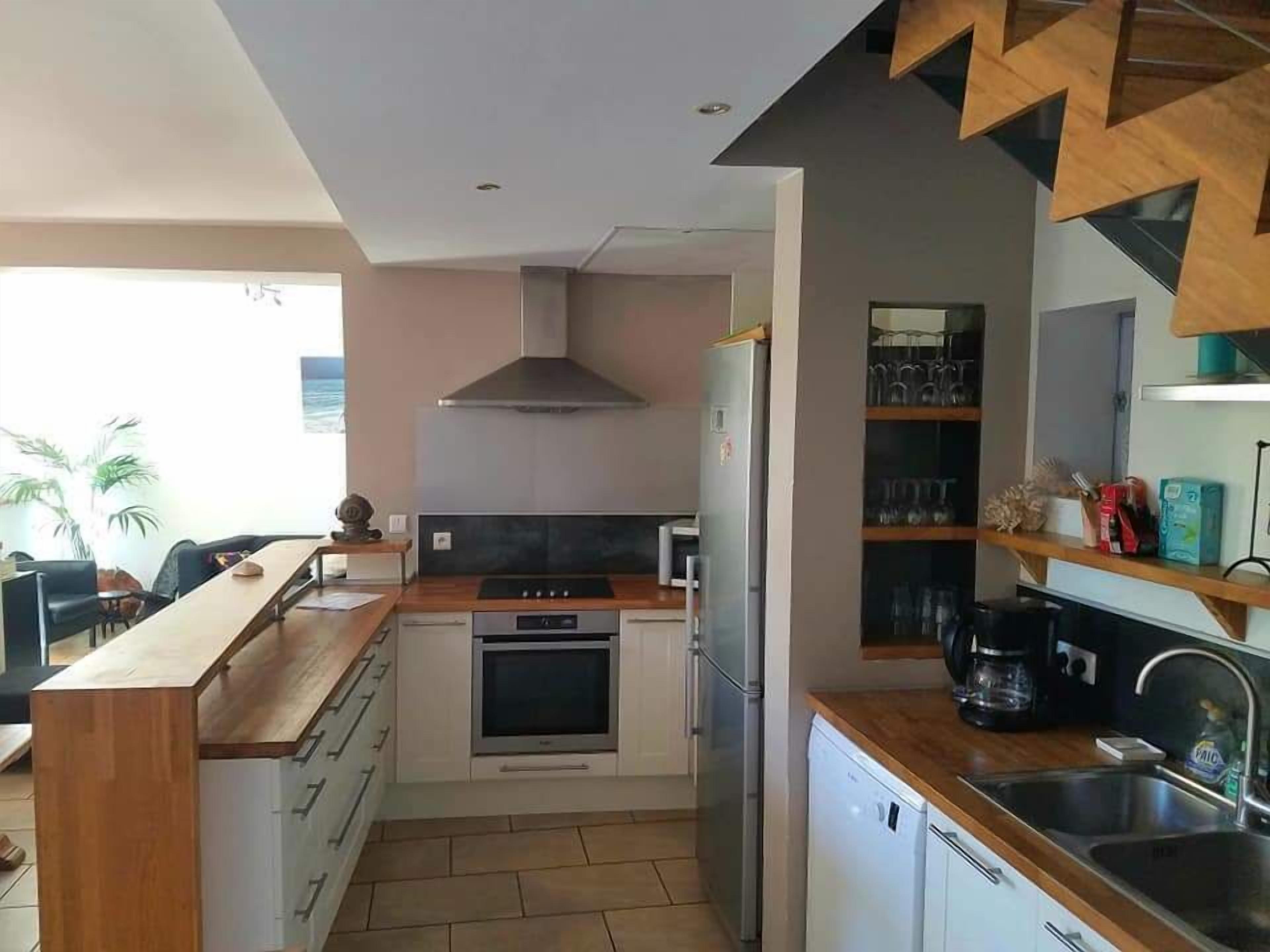 A modern kitchen with a central island, built-in oven, and stainless steel appliances.