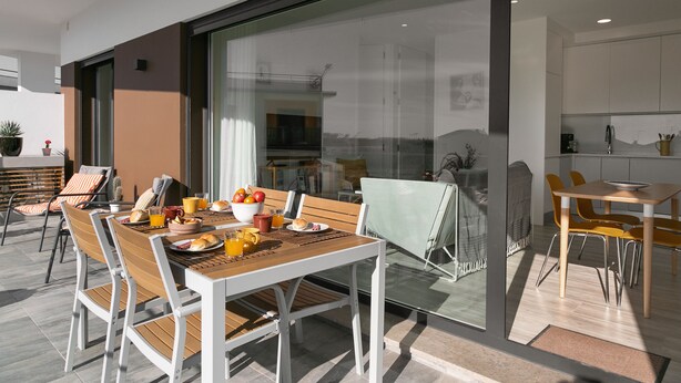Un comedor moderno con una mesa y sillas de madera, un separador de vidrio y vistas a la cocina.