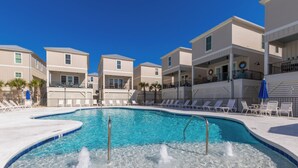 A swimming pool with multiple lounge chairs and a hot tub area.