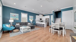A modern living room with a sofa, coffee table, and a dining area with chairs and a table.