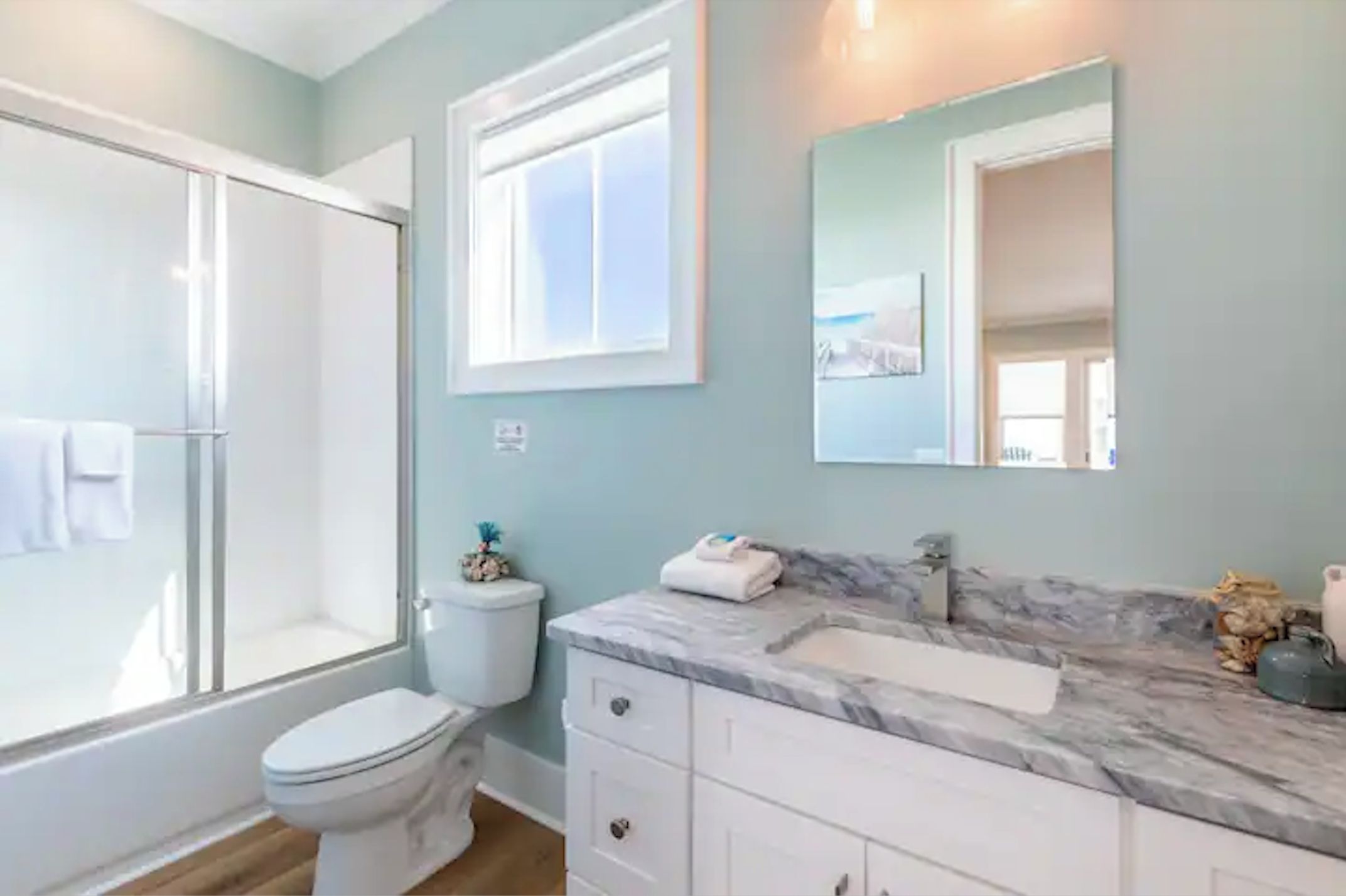 Un baño con ducha, inodoro y tocador con encimera de mármol.