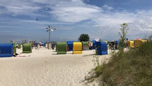 Ein Strand mit bunten Strandsonnenschirmen und einem Windrad.