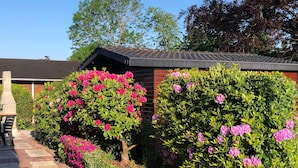 Ein Garten mit einem Ziegelweg, einem Grill und einem Holzhaus mit geneigtem Dach.