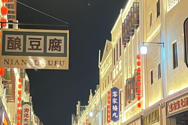 Une vue de rue avec des enseignes illuminées, dont une pour « Nian Dofu » et une autre pour « Coco ».