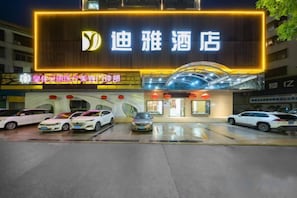 A hotel with a prominent illuminated sign, multiple parking spaces, and a modern entrance.