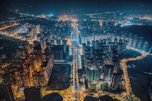 A nighttime aerial view of a densely packed urban area with high-rise buildings and illuminated streets. - Diya Hotel (Meizhou)