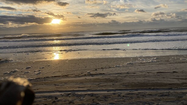 Een strand met golven en een zonsondergang.