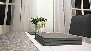 Une pièce avec une horloge au mur, un vase rempli de fleurs et une pile de livres sur une table.