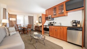 A modern kitchen with wooden cabinets, a microwave, stove, and dishwasher. There is a dining area with a table and chairs, and a living room with a sofa and coffee table. - Cliff Lodge Snowbird  Ski In/Ski Out 2 BR, 3 bath, sleeps 10, 12/31 - 1/7  (Sandy)
