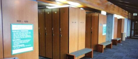 A row of wooden lockers with numbers 605-629, benches, and a trash bin.