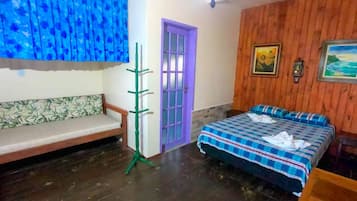 Um quarto com piso de madeira, porta roxa, cama com colcha xadrez, um banco de madeira e um suporte para planta verde.
