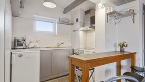 Une cuisine moderne avec des meubles blancs, une table en bois et une fenêtre au-dessus de l’évier.
