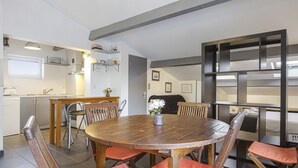 Une cuisine moderne avec un coin repas comprenant une table ronde en bois et des chaises dotées de coussins orange.
