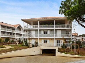 Un hôtel à plusieurs étages doté de balcons, d’une entrée couverte et d’un espace de stationnement.