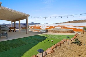 Un patio con zona de barbacoa, mobiliario exterior y un campo de minigolf.