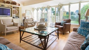 Un salon spacieux avec une table basse en verre, deux canapés et un téléviseur posé sur une étagère.