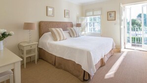 Une chambre à coucher avec un grand lit, des tables de chevet, une lampe et une fenêtre avec des stores.