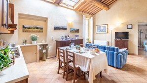 A dining area with a table set for four, wooden chairs, a sofa, and a television. - Apartment in a historic Villa _"FORIPORTA"_view & authentic hospitality in Siena (Siena)