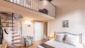 A bedroom with a bed, a chair, a spiral staircase, and a door leading to another room. - Apartment in a historic Villa _"FORIPORTA"_view & authentic hospitality in Siena (Siena)
