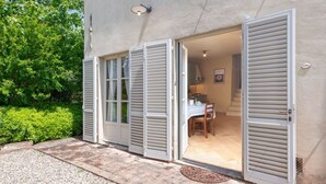 Een modern huis met een patio, een eettafel en een keuken die door de open deuren zichtbaar is.