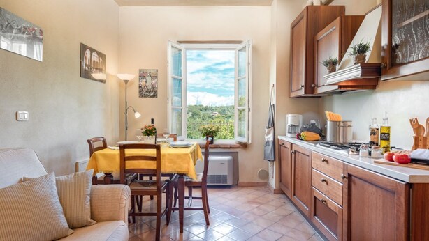 A cozy kitchen with a dining table, wooden cabinets, and a window with a view. - Apartment in a historic Villa _"IL PALIO"_view & authentic hospitality in Siena (Siena)