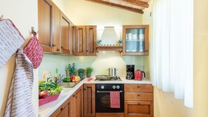 Una cocina compacta con muebles de madera, estufa y cafetera.