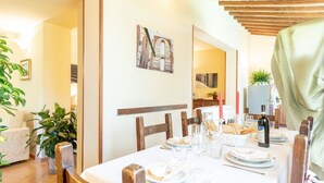 Comedor con una mesa dispuesta para cuatro personas, sillas de madera y mantel blanco.