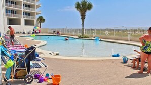A pool area with lounge chairs and a palm tree.