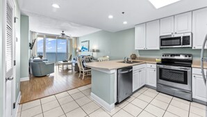 A modern kitchen with white cabinets, stainless steel appliances, and a large island with a sink.