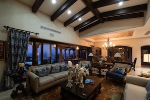 A spacious living room with a high ceiling, large windows, and a view of the outdoors.