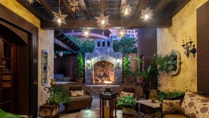 A cozy lounge area with a stone fireplace, wicker furniture, and hanging star-shaped lights.