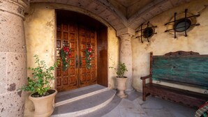 A stone entrance with double wooden doors, a bench, and potted plants.