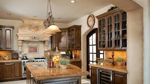 A kitchen with wooden cabinets, a central island, a stove, and a clock on the wall.