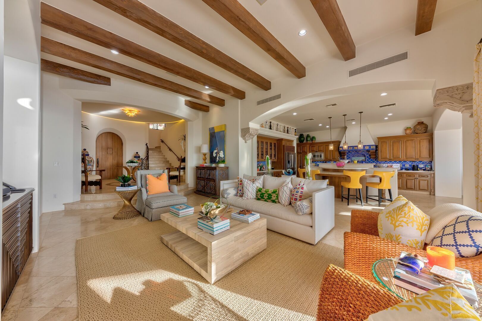 A spacious living area with a high ceiling, wooden beams, and a kitchen in the background.