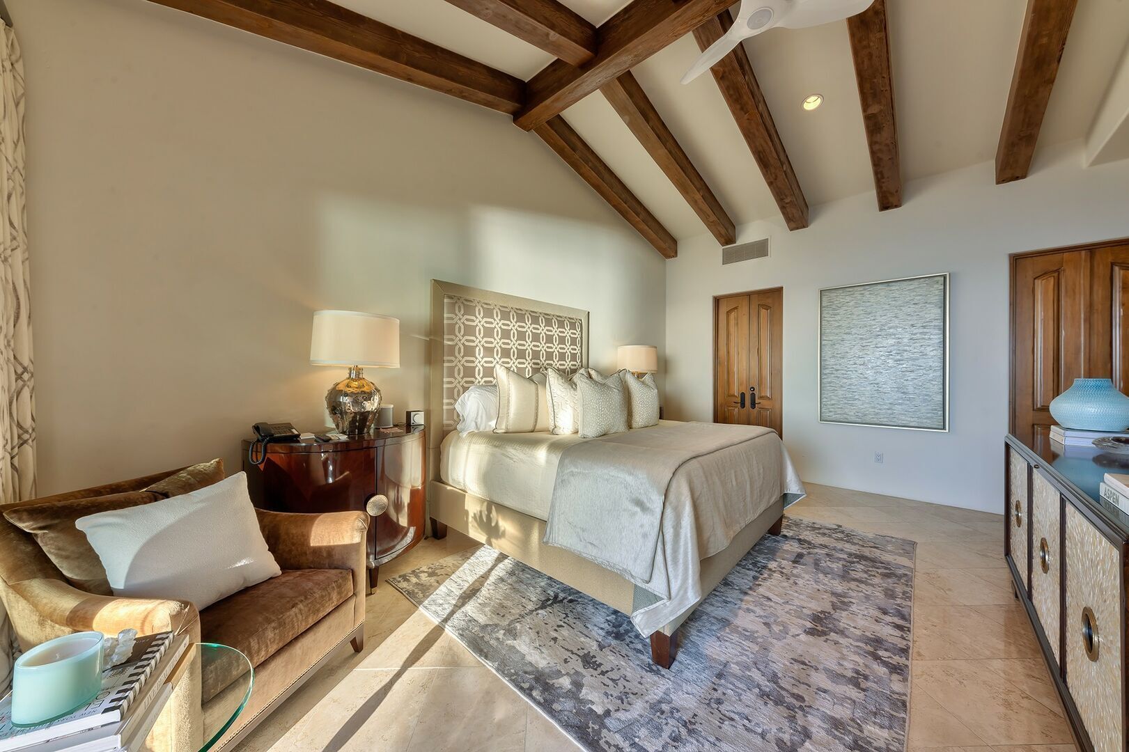 Un dormitorio con cama, mesitas de noche, un sofá y un ventanal grande.