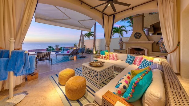Amplia zona de lounge al aire libre con piscina, asientos y vistas al océano.