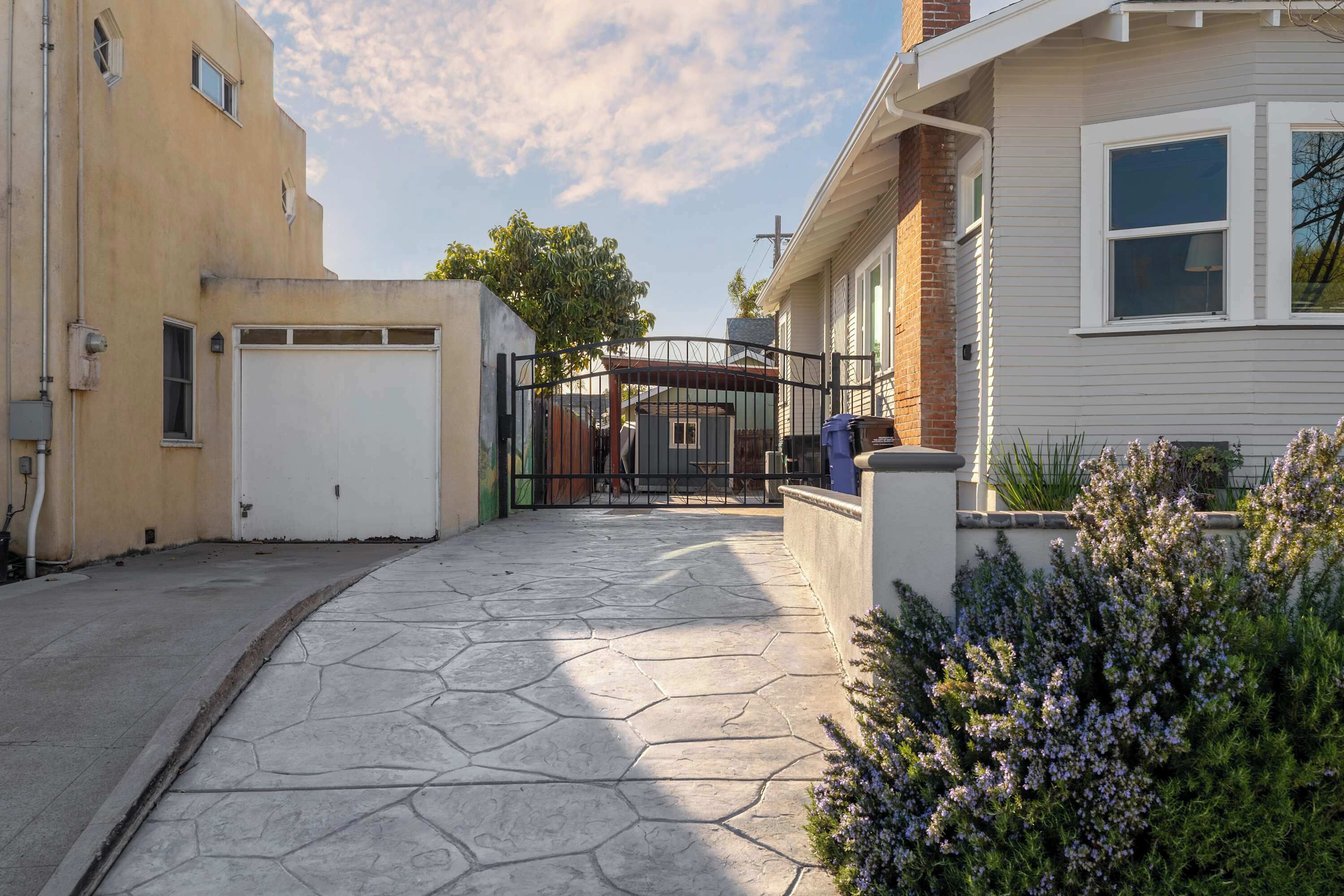 Eine Wohnstraße mit einem gepflasterten Gehweg, einem verschlossenen Eingang und einem Haus mit Garage.
