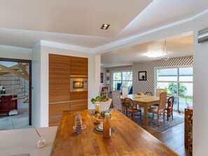 Una cocina moderna con armarios de madera, un microondas integrado y una zona de comedor con mesa y sillas de madera.