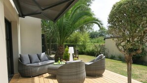 Een terras met een zithoek, inclusief een bank, twee stoelen, een kleine tafel en een lamp.