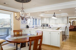 A spacious kitchen with white cabinetry, a central island, and a dining area with a wooden table and chairs.