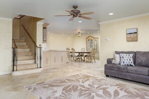 A spacious living area with a gray sofa, a patterned rug, and a dining area with a table and chairs.