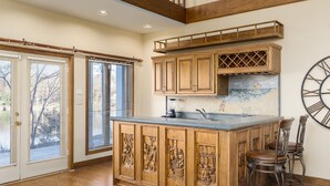 A kitchen with wooden cabinetry, a central island, bar stools, and a large wall clock.