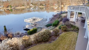 A lakeside property with a dock, outdoor seating area, and a bridge connecting to a house.