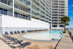 Relax by the pool with lounge chairs and palm trees surrounding a large, curved pool.