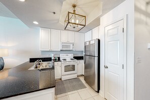 Enjoy cooking in this well-equipped kitchen with a granite countertop, stainless steel appliances, and white cabinetry.